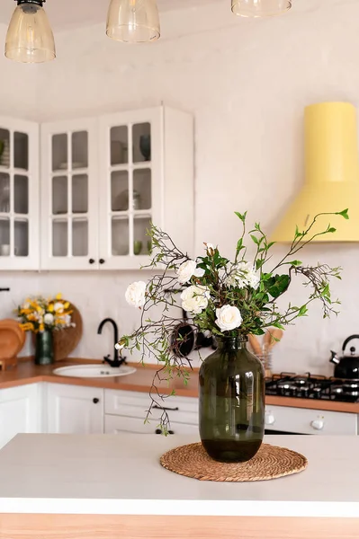 木製のテーブルの上に花の花束 背景には スカンジナビアスタイルの白いキッチンのインテリア 家の快適さのコンセプト ロイヤリティフリーのストック写真