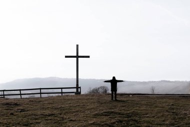 Din teması, katolik haç görüşü ve insan silueti, fantastik manzaralı ve arka planda dağlar. Boşluğu kopyala