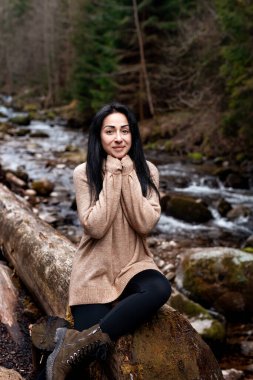 Genç esmer kadın dünya çapında yeni, büyülü ve fantastik yerleri keşfediyor. Ormanda rahatlayan ve neşeyle gülümseyen genç bir kadının portresi.