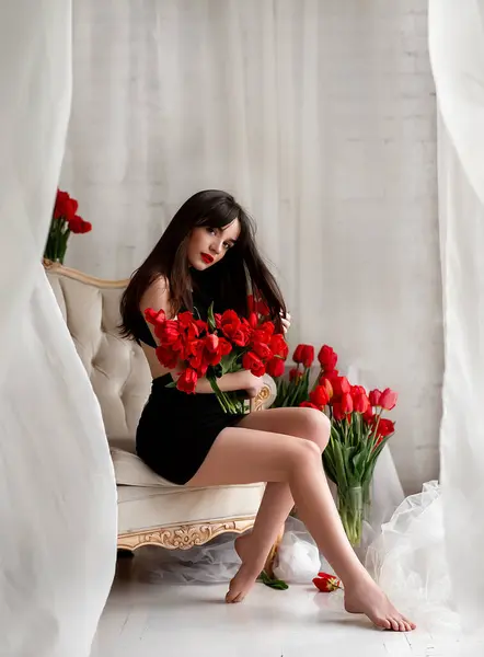 花を持った魅力的な若い女性 チューリップの花束を持つ美しいブルネットの少女 チューリップを保持する美しい官能的な女性 ストック写真
