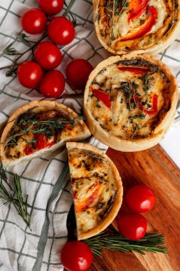 Lezzetli bir domates ve sebzeli tart taze kiraz domatesleri sergiliyor, ahşap bir tahtanın üzerinde mükemmel pişirilmiş.