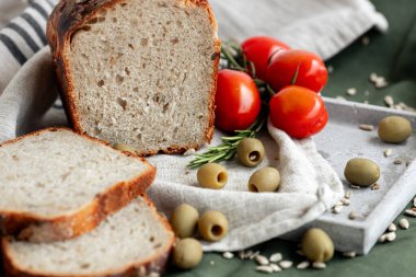 Nefis dilimlenmiş bir zanaatkar ekmeği sulu domatesler ve kırsal kumaş üzerinde zeytinlerle birlikte güzelce düzenlenir..