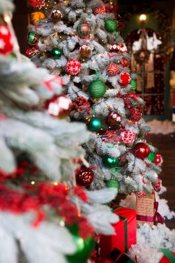 Güzel dekore edilmiş bir Noel ağacı, canlı süslerle süslenmiş ve sevgi dolu hediyelerle çevrili.