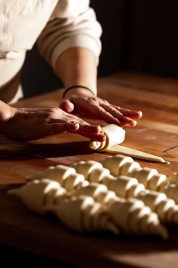 Çok yetenekli bir fırıncı, hamuru titizlikle ahşap bir yüzeyde mükemmel ve zarif hamur şekillerine dönüştürür.