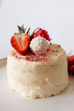 Yumuşak kremalı, çilekli, incili, çiçekli ve beyaz mantarlı küçük bir kek..