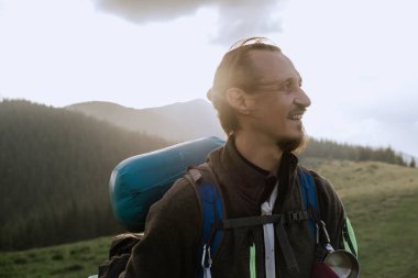 Gülümseyen yürüyüşçü, Ukrayna 'daki özellikle Khomiak Dağı yakınlarındaki Karpat Dağları' nın manzarasının keyfini çıkarırken büyük mavi bir sırt çantası taşıyor..