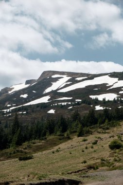 Svydovets dağlarının görkemli karla kaplı zirveleri, Ukrayna 'nın batısında, parçalı bulutlu bir gökyüzünün altında. Doğa ve macera temaları için ideal.