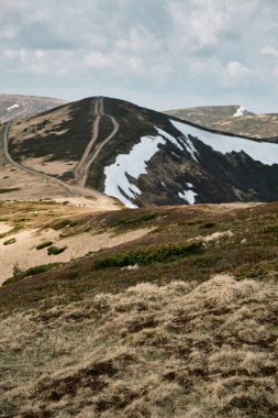 Batı Ukrayna 'daki Svydovets dağlarının görkemli kar tozlu dağları parçalı bulutlu bir gökyüzü altında engebeli araziler ve sakin manzaralar sergiliyor..