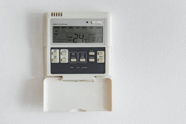 Beyaz bir duvarda elektronik termostat var.