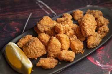 Tabağında bir dilim limon olan çıtır ev yapımı nuggetlar.