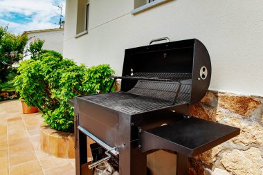 Arka bahçede siyah barbekü fırını.