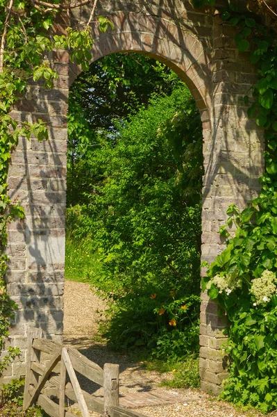 英国のカントリーガーデンにつながるレンガの壁のゲートウェイ — ストック写真
