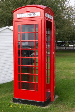 Geleneksel İngiliz kırmızı telefon kulübesi. Kapı hafifçe açık.