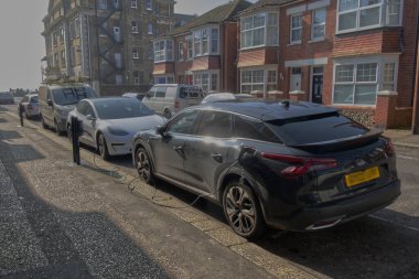 Şehir caddesinde elektrikli araç şarj ediliyor. Worthing, Batı Sussex, İngiltere. Plakalar bulanıklaştı.