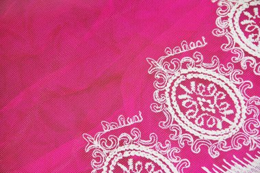Beyaz dantel kumaş dokusu ve pembe arka planda çiçek süsü.