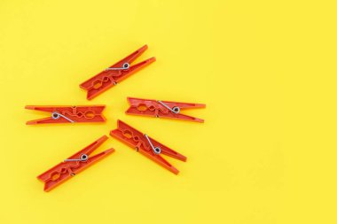 Çamaşırları ipe bağlamak için plastik mandallar, sarı arka planda izole etmek için.