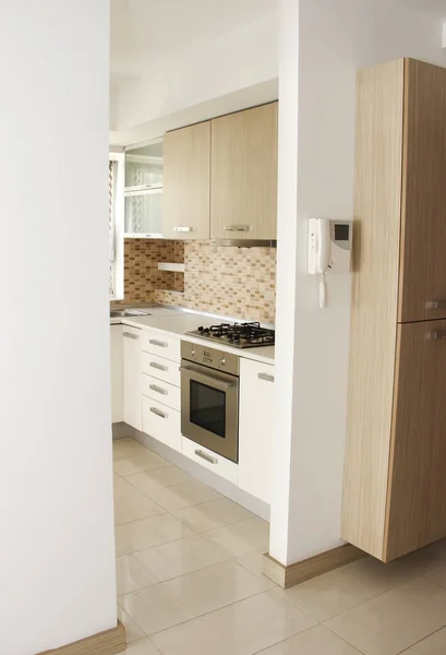 The interior of the kitchen with beige furniture with cabinets, shelves and appliances for cooking