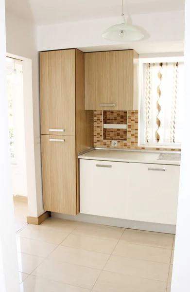 The interior of the kitchen with beige furniture with cabinets, shelves and appliances for cooking