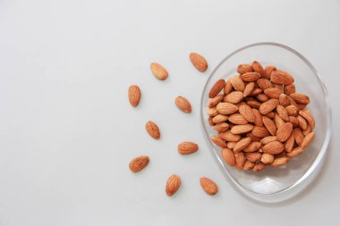 Gri bir zemin üzerinde şeffaf cam plaka içinde kahverengi badem taneleri