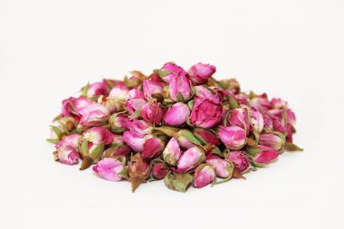 Kurumuş tomurcuklardan ve beyaz arkaplanda pembe bir gülün yapraklarından yapılmış çay.