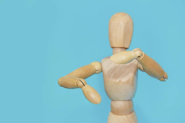 yellow wooden mannequin gestures with his hands on a blue background