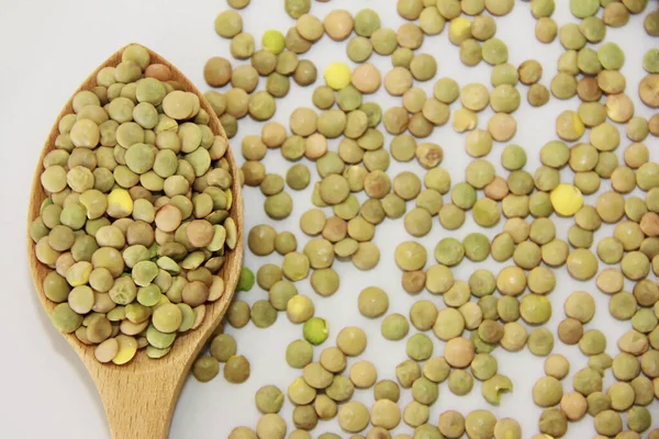 stock image small grains of natural green lentils in a wooden spoon on a gray background