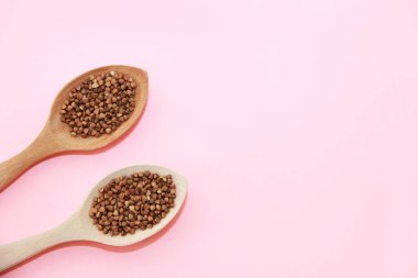 Tahta bir kaşıkta küçük doğal kahverengi karabuğday taneleri.