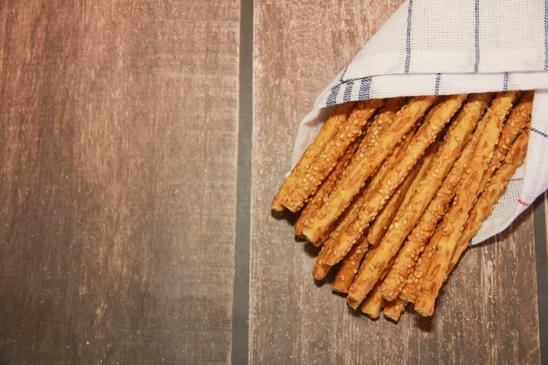 Long dry sesame bread sticks on a brown background