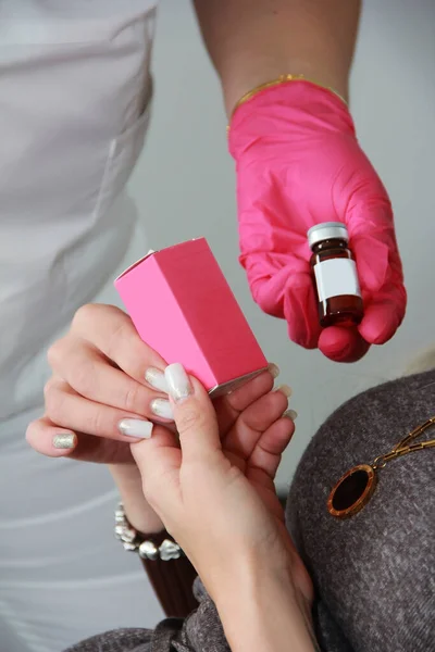 Beautiful women\'s manicured hands and doctor\'s hands in pink gloves are holding medications