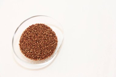 Small brown grains of natural buckwheat in a decorative transparent glass plate
