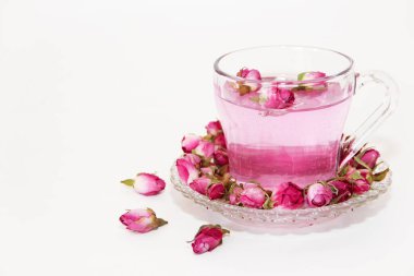 Pink tea in a clear glass mug and dry little pink rose buds