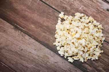 White fried popcorn on a brown wooden background