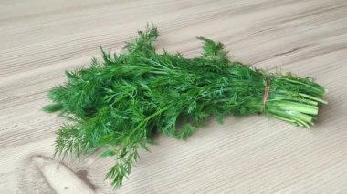 Ahşap bir arka planda yakın planda bir demet yeşil dereotu.