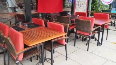 Şehir kafesinde boş ahşap masalar ve plastik kırmızı sandalyeler.