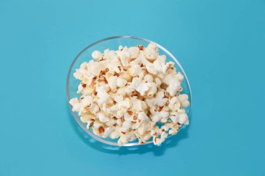 Mavi zemin üzerinde şeffaf cam plaka içinde beyaz kızarmış patlamış mısır.