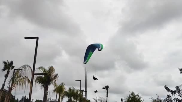 一个人骑着蓝色的滑翔伞在多云的灰色天空中飞行 — 图库视频影像