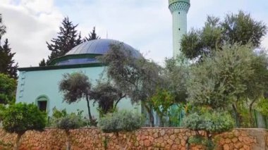 Antalya, Türkiye, 21 Mart 2023. Mavi gökyüzüne karşı minaresi ve yeşil bahçesi olan geleneksel Türk doğulu camii