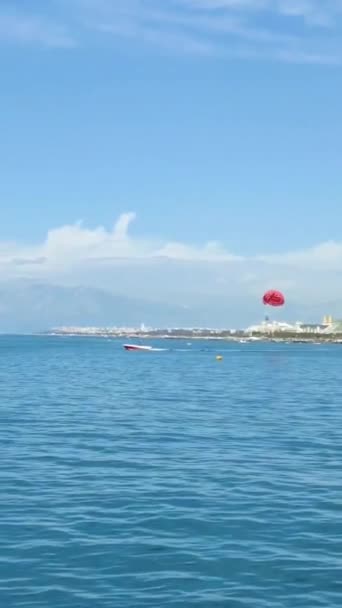 アンタルヤ トルコ 2023年5月14日 地中海上の青い空を飛ぶ船に取り付けられた赤いパラシュート — ストック動画