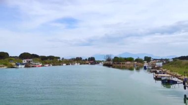 Yeşil kıyıları olan sakin bir nehir ve beyaz bulutlu mavi bir gökyüzü.