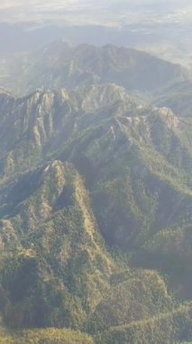Yeşil ormanı olan bir dağ sırası, yukarıdan bir uçak penceresinden açık bir manzara.