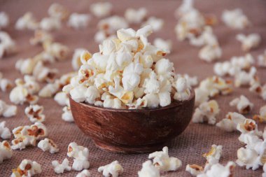 Kahverengi arka planda ahşap bir tabakta tatlı kızarmış havadar patlamış mısır.