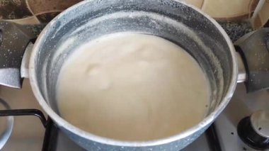 Beyaz doğal süt kaynatılır ve gri bir tencerede fokurdar.