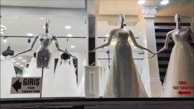 Aydınlatılmış bir mağazanın camında beyaz kadın gelinliği