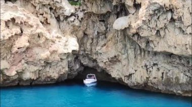 Mavi Akdeniz 'in güzel manzarası kayalık bir kıyısı ve beyaz yüzen bir teknesi var.