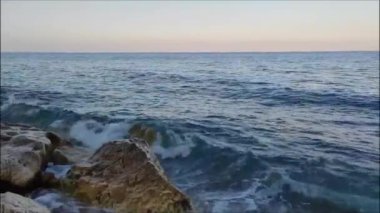 Mavi Akdeniz 'in güçlü dalgaları kumlu sahile büyük taşlarla gelir.