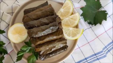 Geleneksel oryantal Türk dolması pirinç ve etle doldurulmuş üzüm yaprakları maydanoz ve limon dilimleriyle dolu bir tabakta yatıyor.