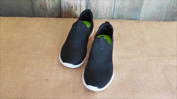 Zapatillas Deportivas Negras Con Suelas Blancas Sobre Fondo Marrón — Vídeos de Stock