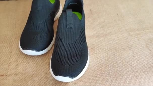 Zapatillas Deportivas Negras Con Suelas Blancas Sobre Fondo Marrón — Vídeo de stock