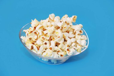 Mavi arka planda şeffaf bir tabakta beyaz, kızarmış patlamış mısır.