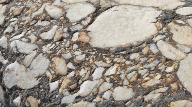 Eski taş bir duvarın dokusu beyaz mermer parçaları ve gri çakıl taşları, çatlaklar ve damarlarla